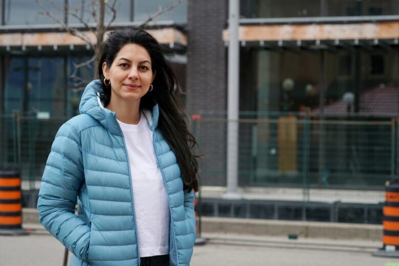 A woman wearing a white T-shirt and blue coat poses for a picture.