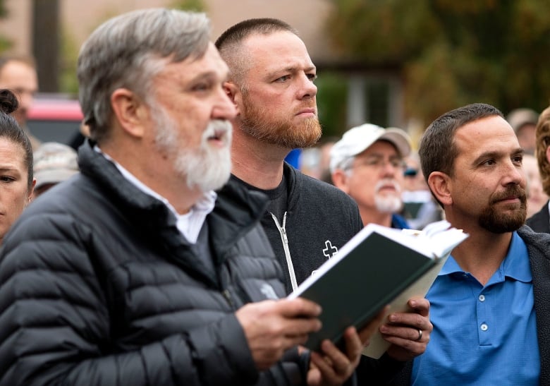 Christ Church Pastor Doug Wilson, center, and Latah County Commission candidate Gabriel Rench, center, sing a hymn over the noise from counter-protesters playing drums during 