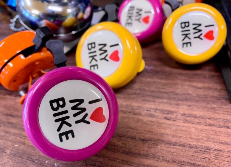 Four small bright yellow and pink bike bells with the words 