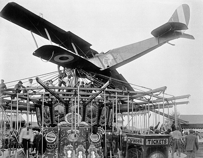 A plane sits on top of a merry-go-round in a black-and-white photo.