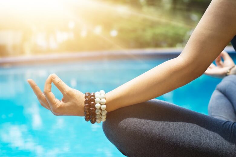 A hand showing a meditation sign resting on a leg.