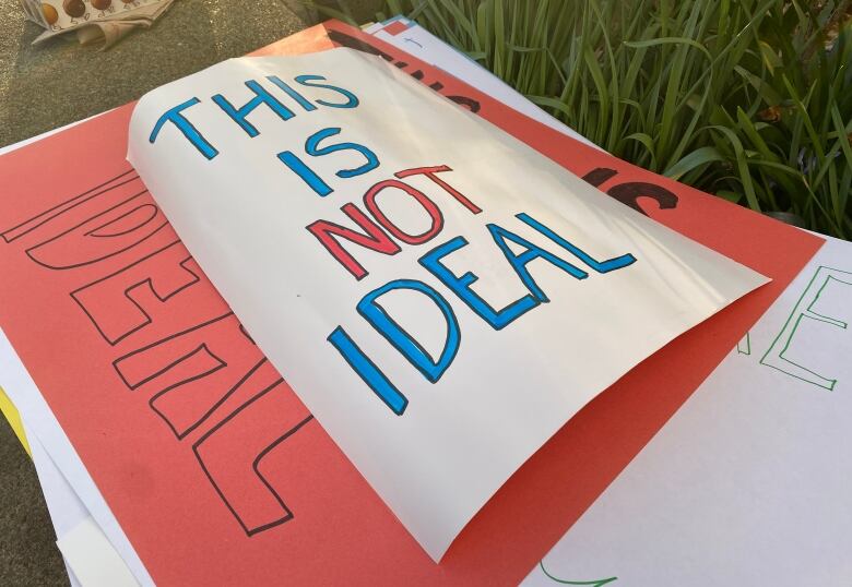 A stack of hand-drawn placards is shown with the top one reading 