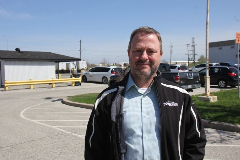 A man in a black jacket looks into the camera