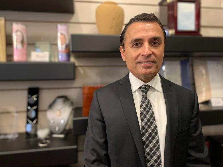 Kamal Bhardwaj stands in front of urns and candles in the funeral home's selection room.