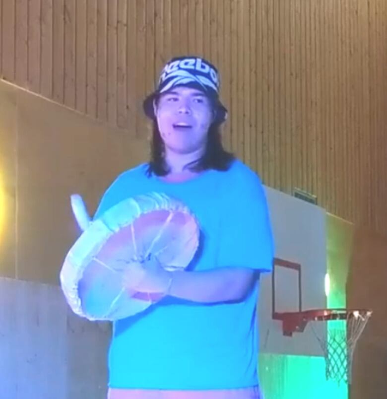 An Indigenous man sings and beats a drum.