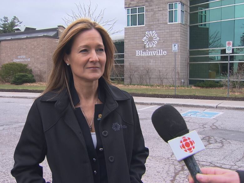 A woman standing outside partaking in an interview with CBC. 