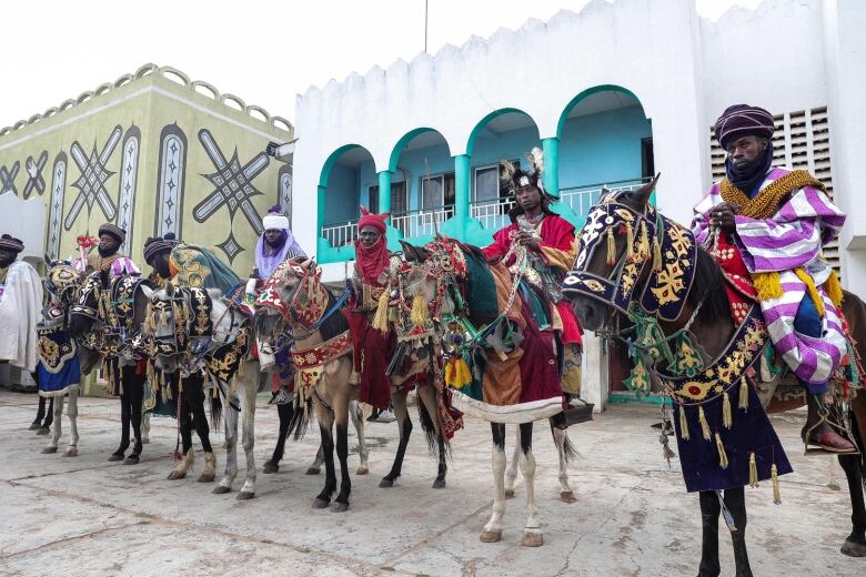 A group of men on horses in their regalia side by side, attending the Durbur Festival in Nigeria.