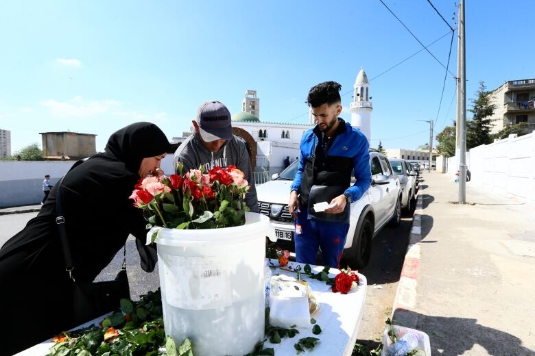 Youths sell flowers at the entrance of a cemetery, as Muslims visit relatives' tombs after Eid prayer.