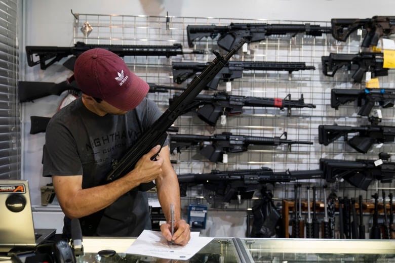 A man holds up a firearm in a gun store.