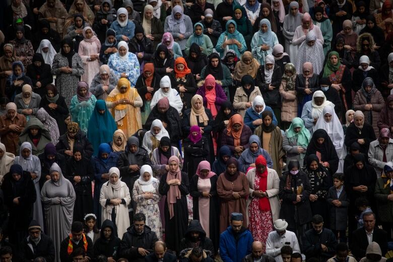 Rows of people in the stands of a stadium pray