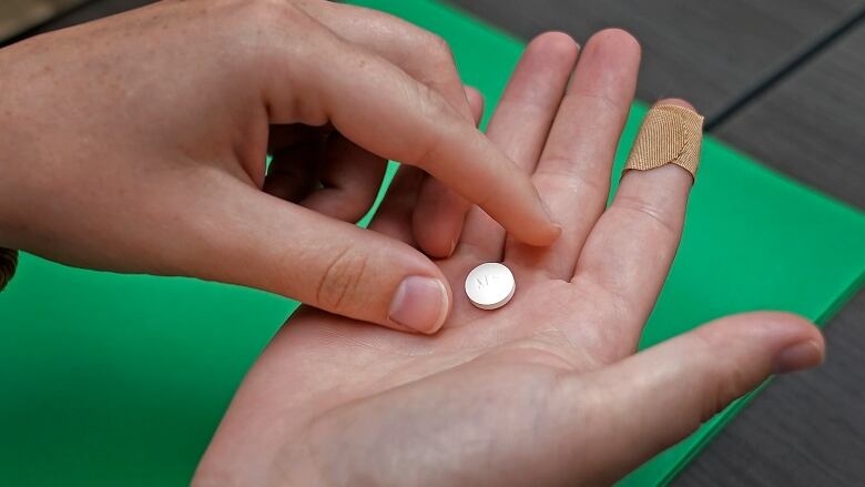 A person picks up a pill from their hand.