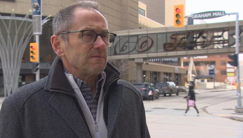 A man is pictured looking forward. Behind him, 'Go Jets' is painted on a downtown skywalk.