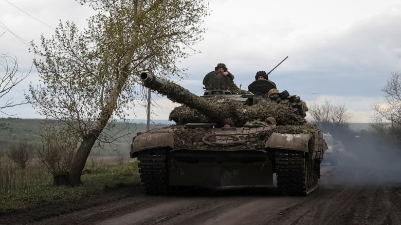 Ukrainian soldiers ride in a tank.