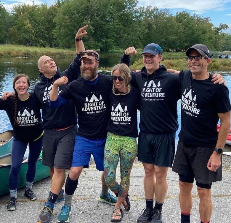 Dave Greene and the Night of Adventure team outside by a river and canoes. 