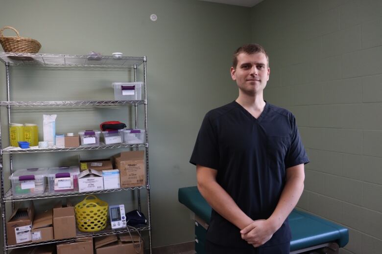 A person in scrubs stands in front of a patient bed.