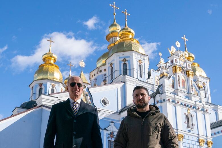 Two men are shown in front of an ornate church in an outdoor photo.