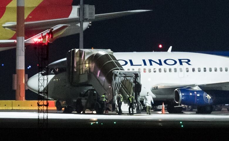 Officials in protective clothing are seen outside a plane at Vancouver International Airport, a few weeks before the pandemic was declared.