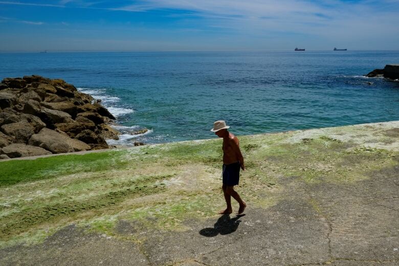 A man walks along a beach.