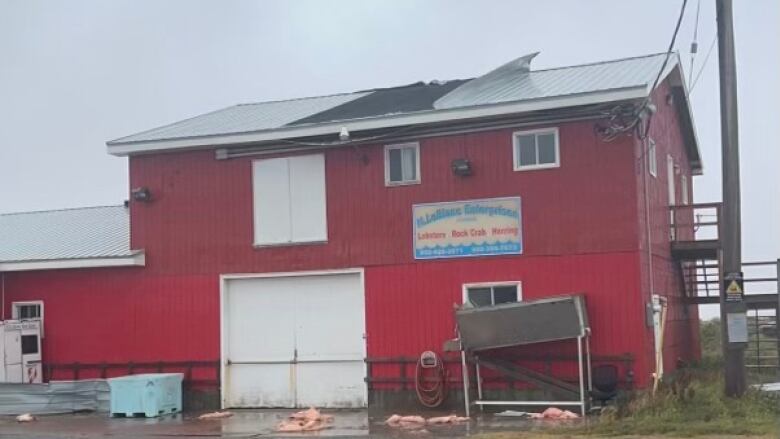 a 2-storey red building is seen with metal sheets on its roof bent backwad