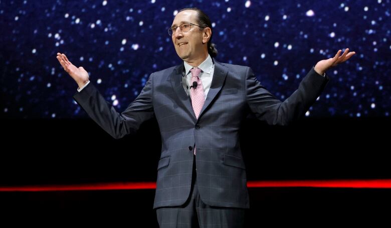 A man gestures while speaking onstage.