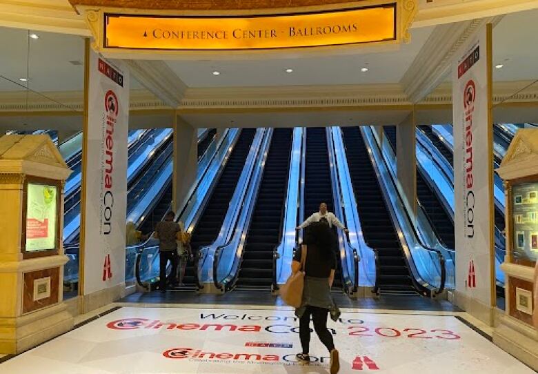 A woman walks towards several escalators.