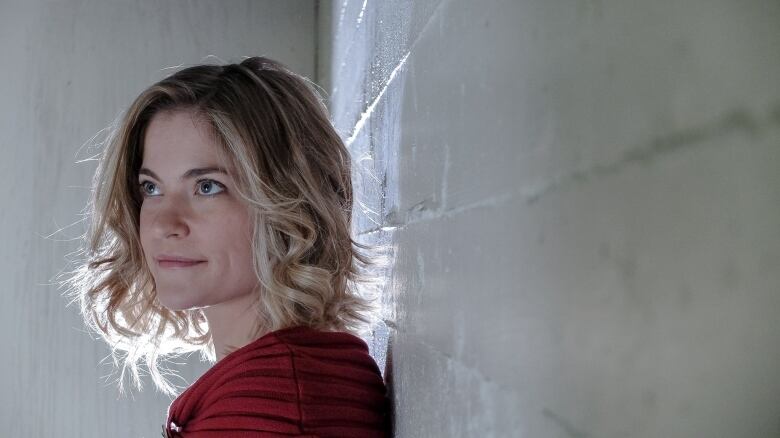 A woman leans on a wall.