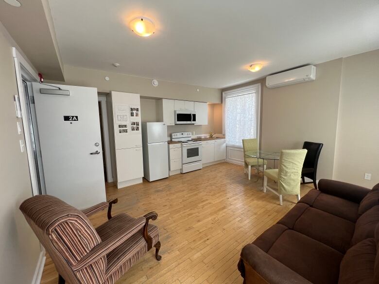 The interior of a furnished living room and kitchen area.