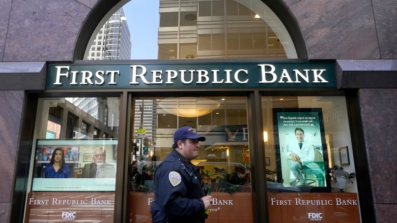 A man in a uniform is shown walking in front of a building which displays the lettering 'First Republic Bank' above the door.