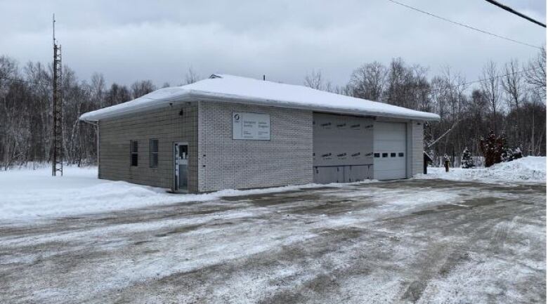 A one-storey grey brick building sits on a plowed parking lot 