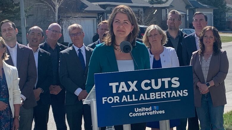 A woman stands at a podium with people behind her.