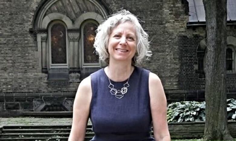 Audrey Macklin sitting on a bench outside. 