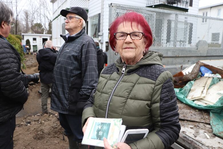 A woman with red hair carries a photo album. 