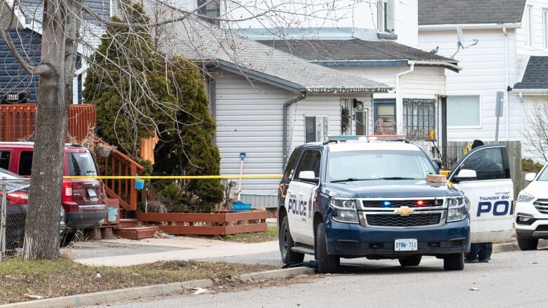 A police vehicle is parked on a street. It's in front of yellow police tape. 