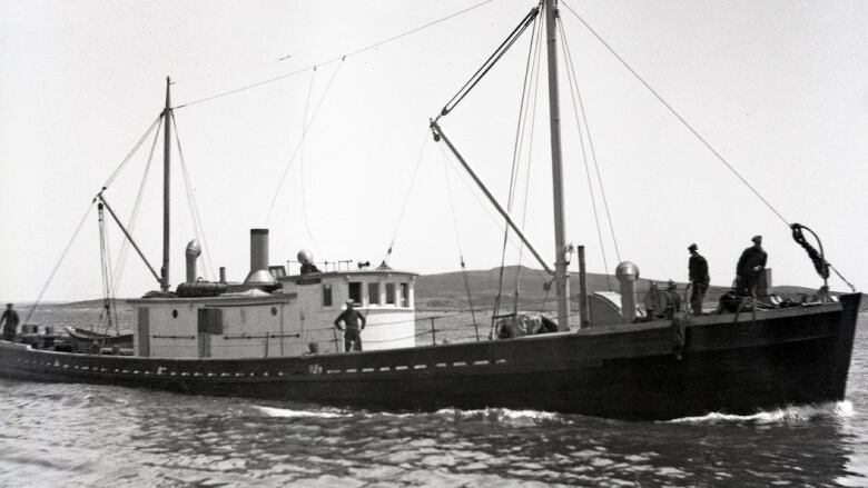 A black and white picture of a long fishing ship.