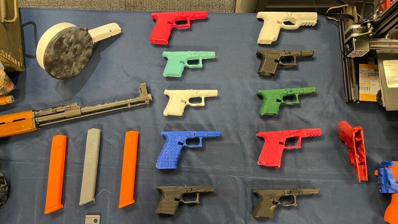 A variety of 3D-printed gun parts on a table. 