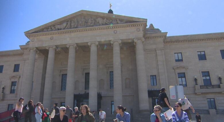 A group of ralliers are pictured on the steps of a government building.