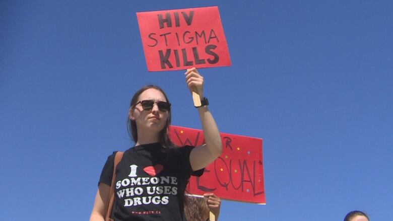 A woman is seen holding up a sign that says 