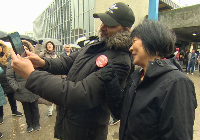 Women poses for a picture with a man with striking workers standing nearby.