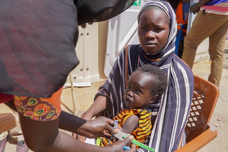 A baby has their arm measured to check for malnutrition at a refugee camp for people who crossed from Sudan in Renk County, South Sudan, on Wednesday, May 3, 2023. 