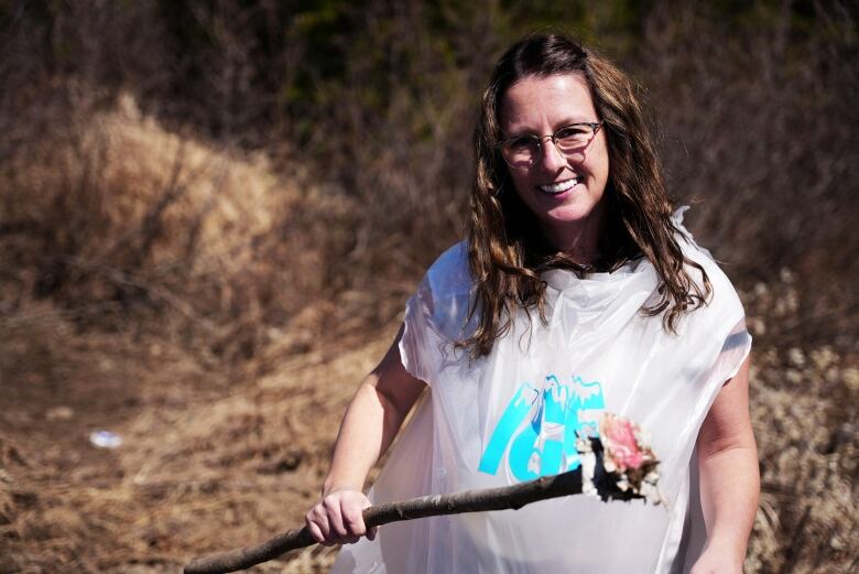 A woman in a white garbage bag with 'ice' on the front is shown picking up trash and smiling at the camera. 