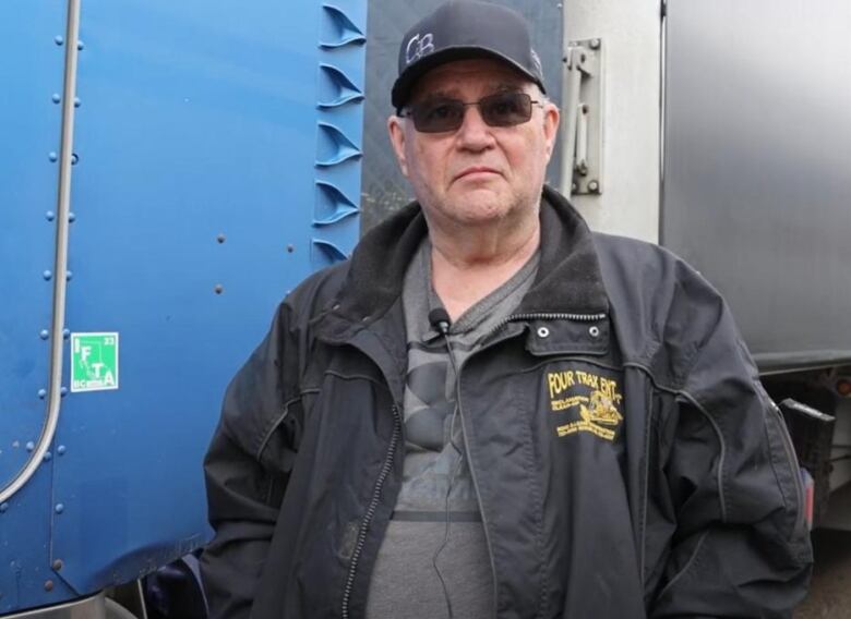 A man stands in front of a large truck.