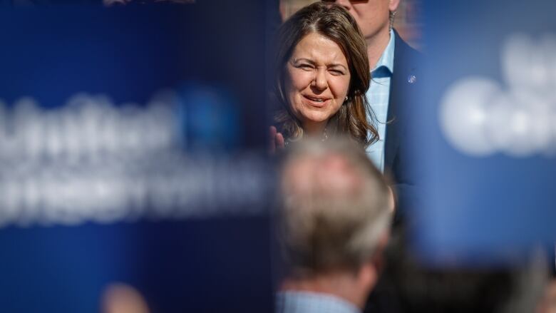 UCP leader Danielle Smith is flanked by two large blue United Conservative signs in the foreground