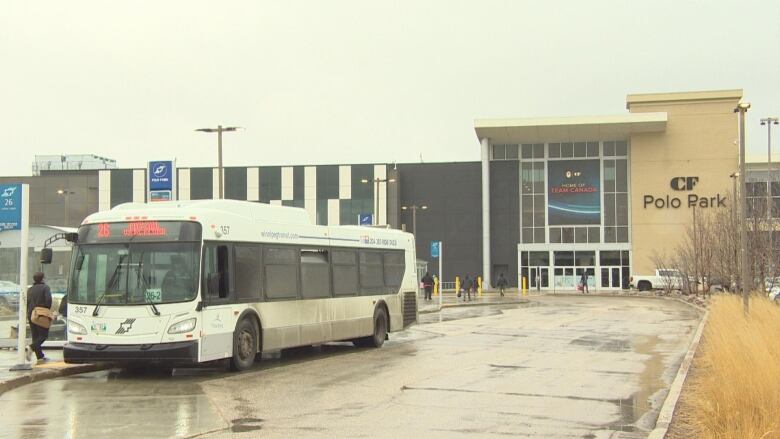 A transit bus stops at a bus stop outside a mall.