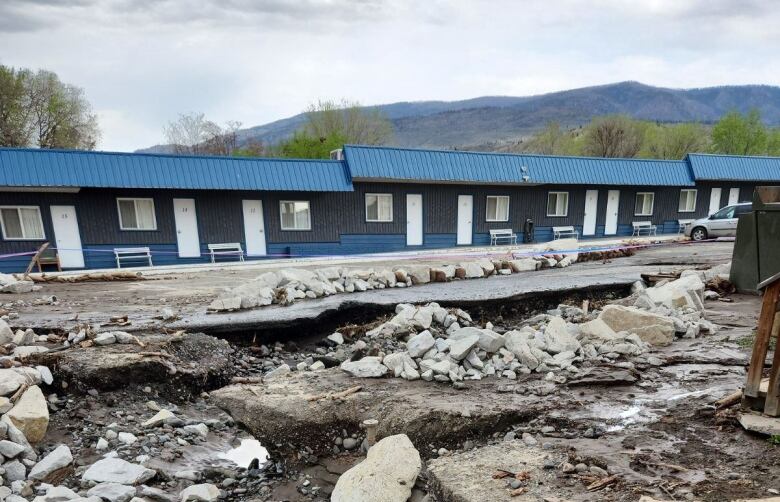 A road is seen ripped up due to flood damage in a rural environment.