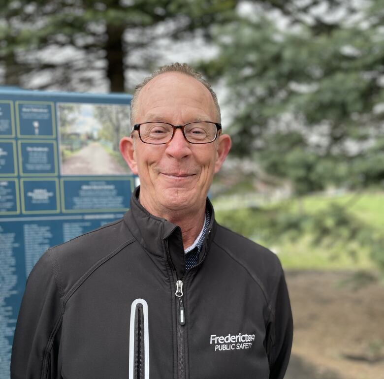 Man smiling next to trail sign. 