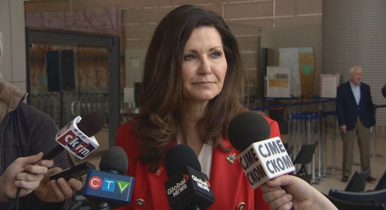 A woman with multiple microphones pointed at her is being interviewed. 