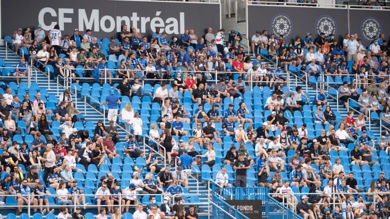 There are people sitting in seats at a sporting event.