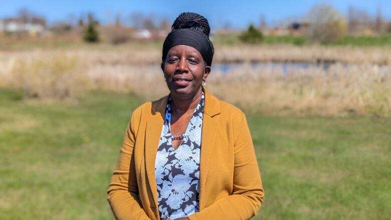 A woman stands with a pond in the background 