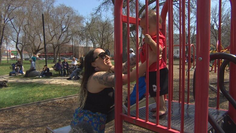 A mother goes to pick up her son on a park play structure.