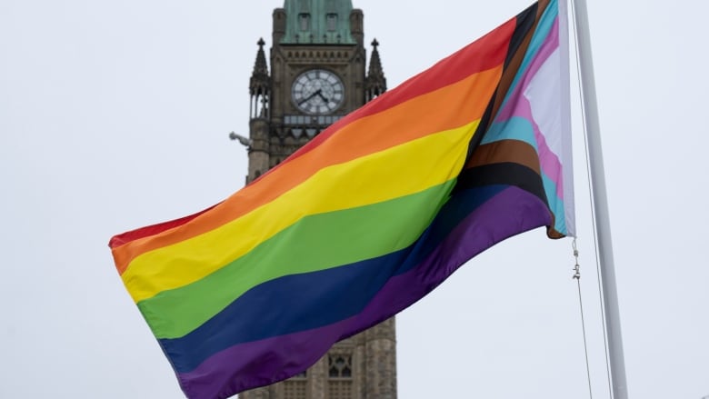 A rainbow flag flies in front of Parliament Hill buildings.